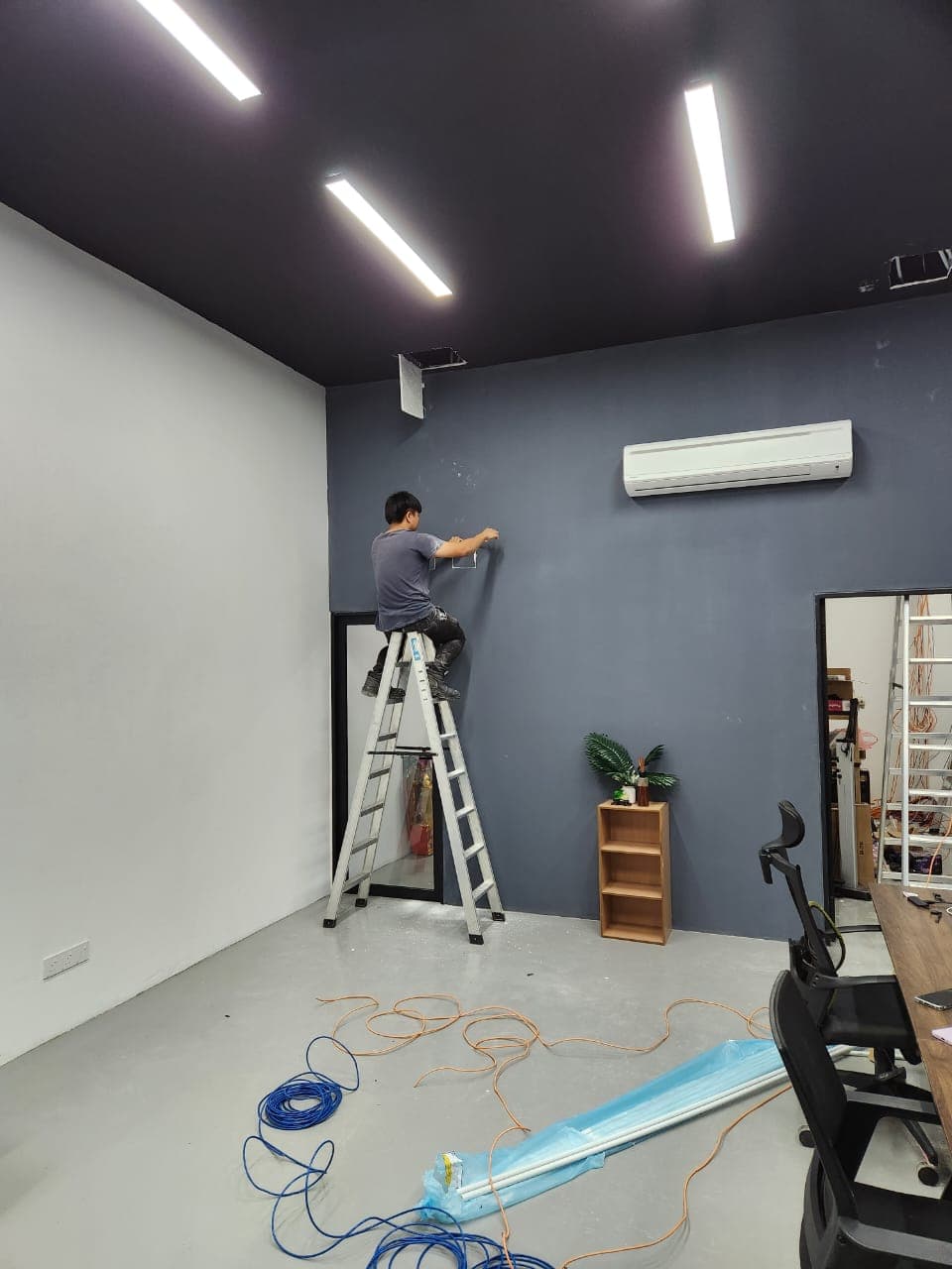 Installer on a ladder running ELV cabling for alarm and security system installation